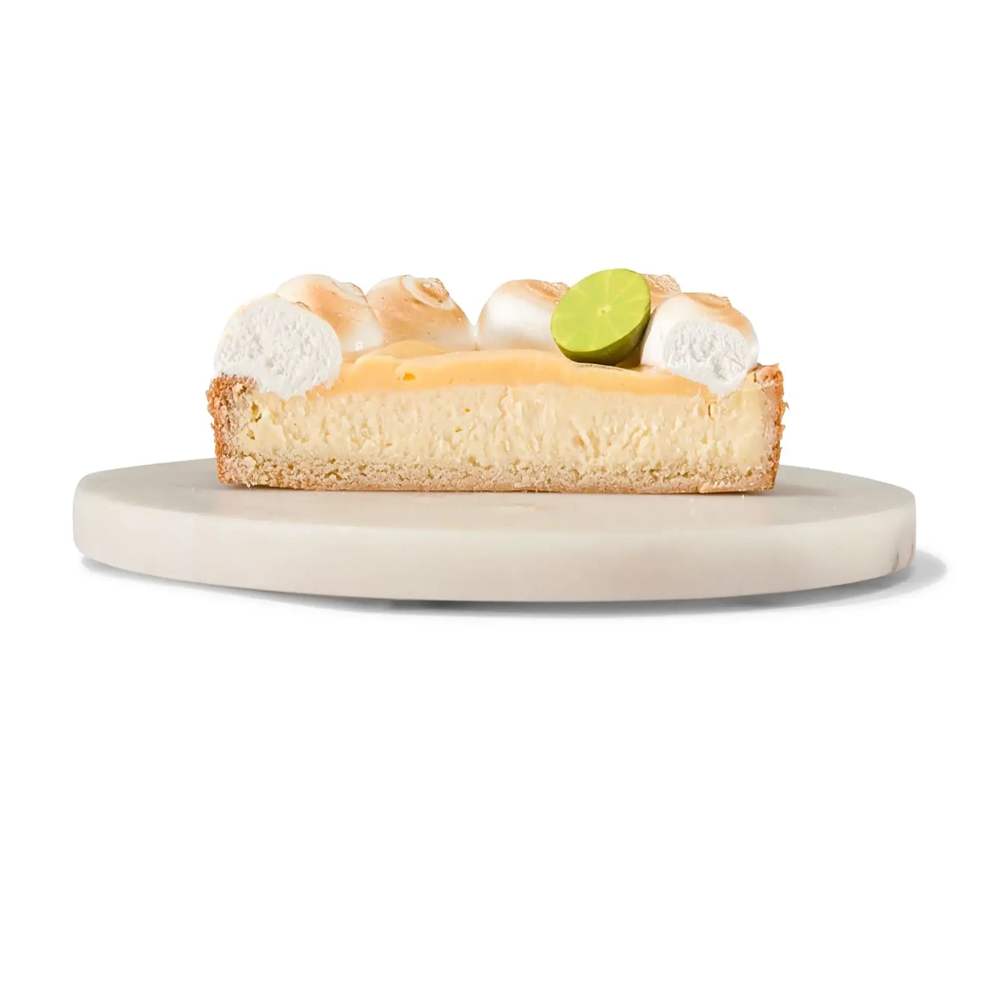 Doorsnede van citroen meringue cheesecake op een serveerbord, met een plakje limoen als garnering