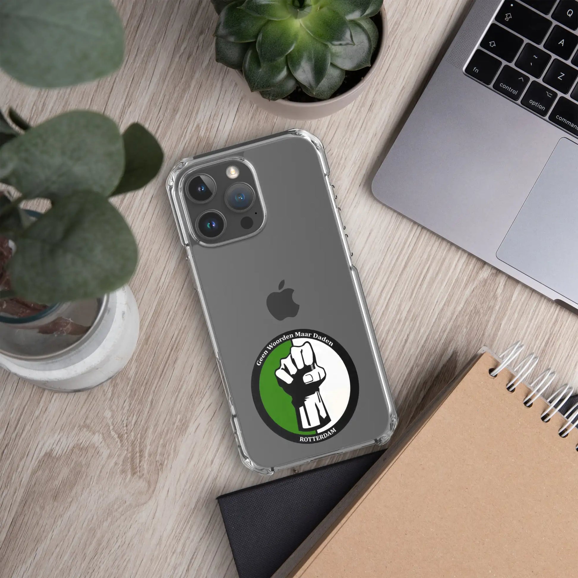 Feyenoord iPhone 16 hoesje met Geen Woorden Maar Daden logo, beschermende case naast laptop en planten op bureau.