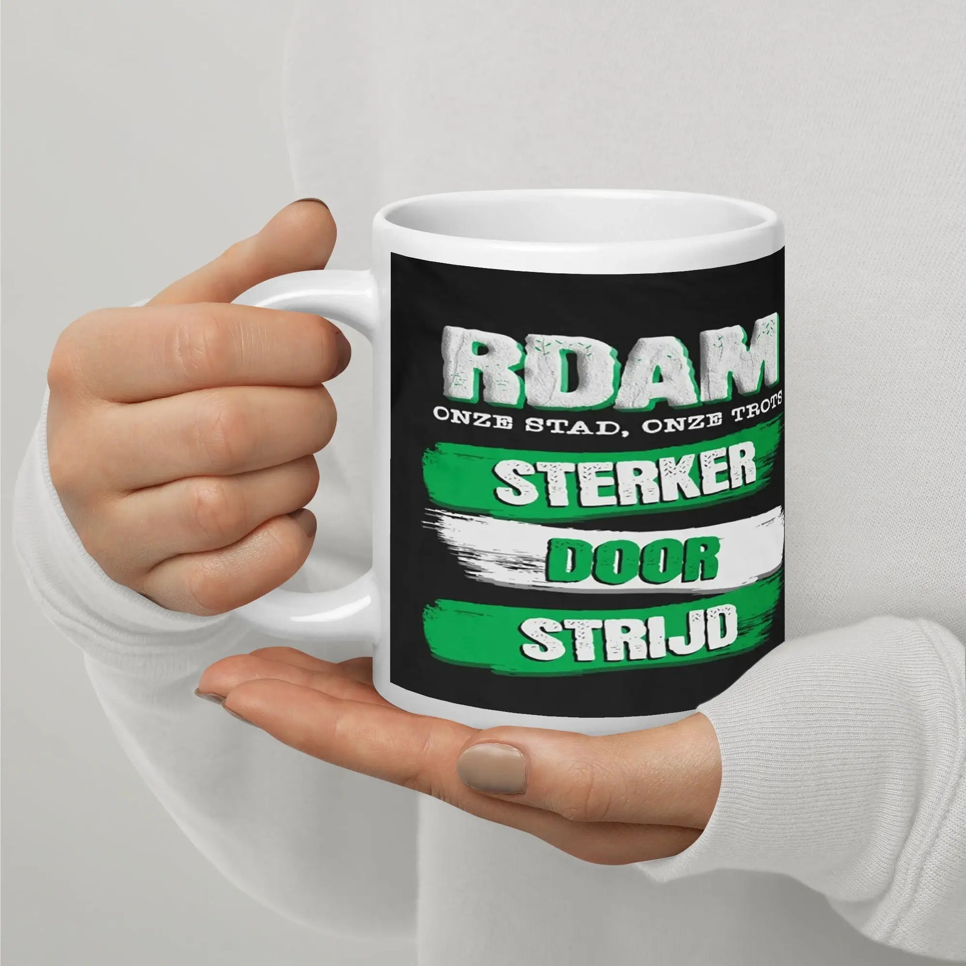 Hand houdt een Rotterdam mok met de tekst 'Sterker door Strijd' vast - Uniek cadeau voor Rotterdammers.