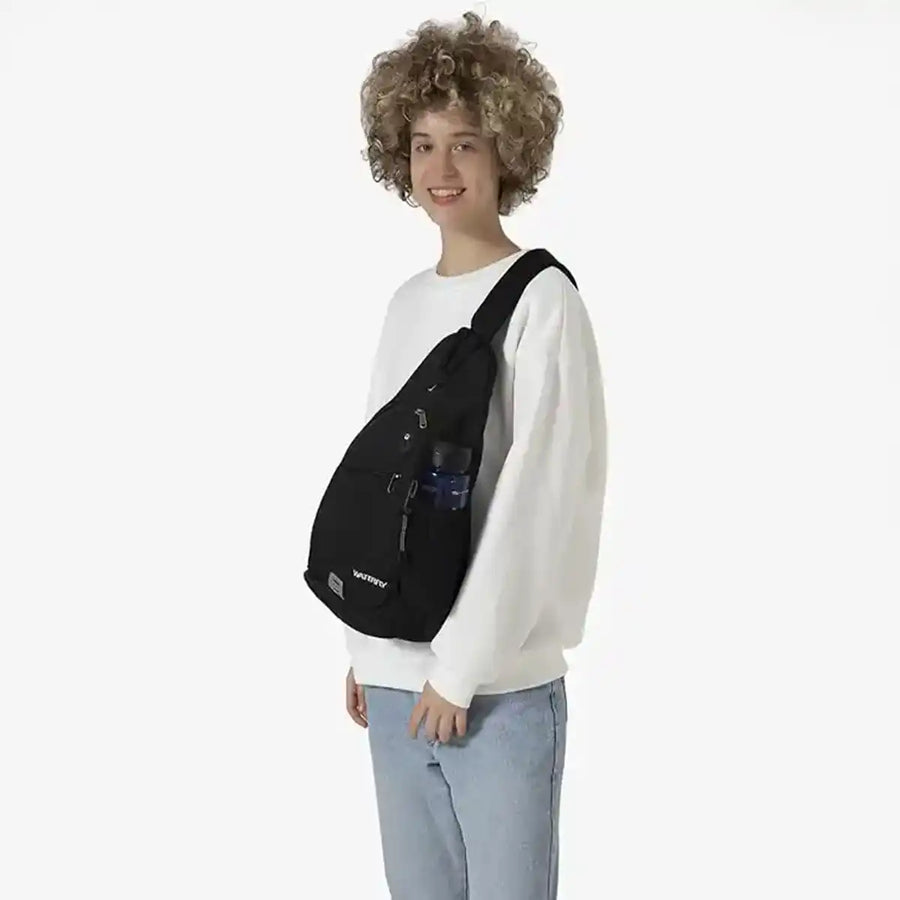 Model draagt zwarte sling rugzak, anti-diefstal crossbody tas voor reizen en wandelen.